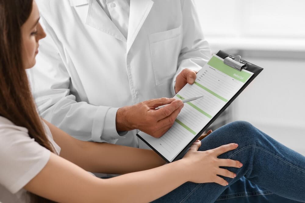 Doctor showing medical card to patient in clinic, closed