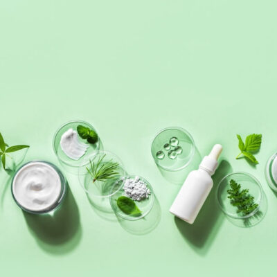 Organic skin care cosmetic products, natural plant ingredients on green background, copy space, banner.